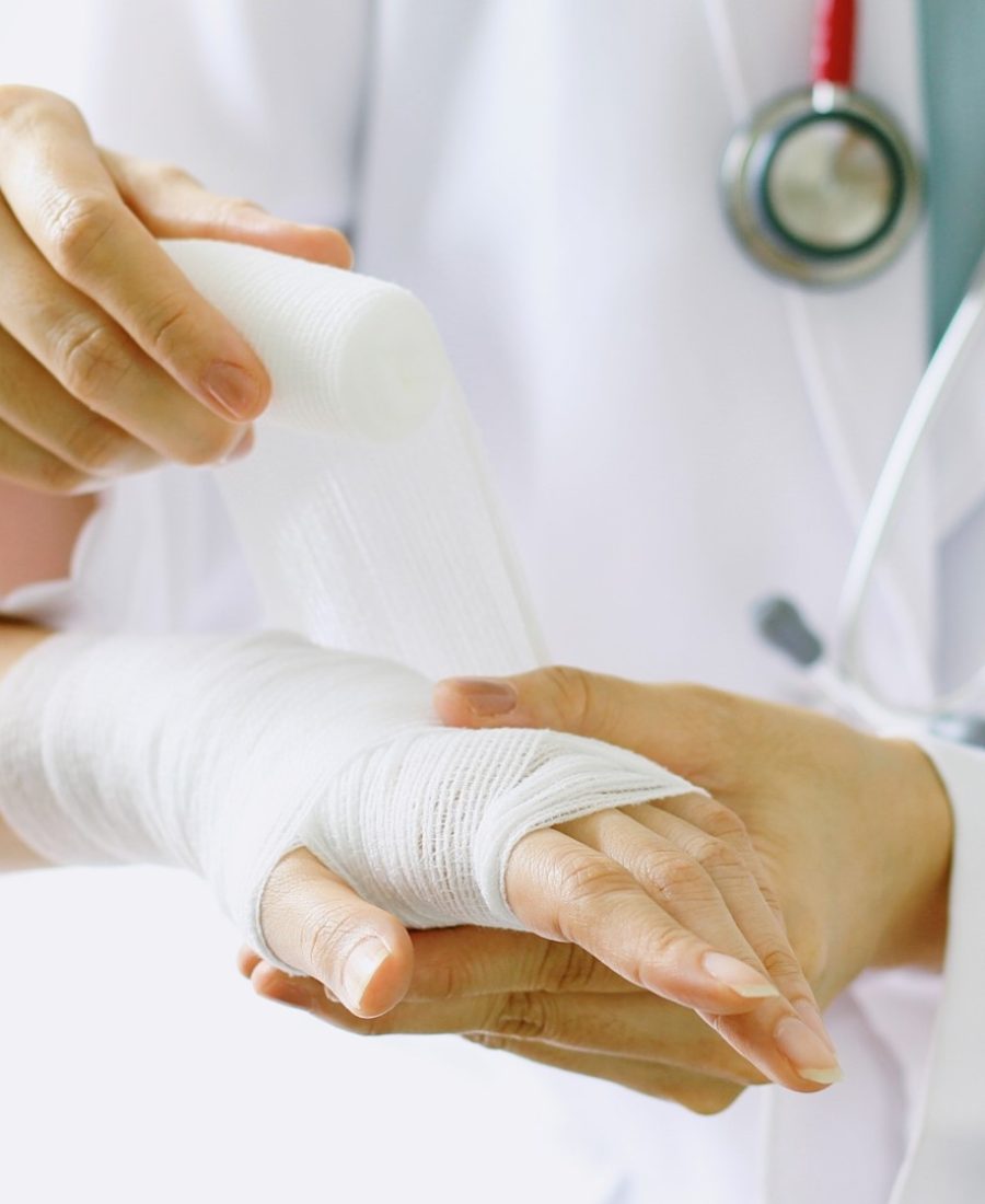 Close-up of female doctor with stethoscope bandaging hand of patient. (Selective Focus)